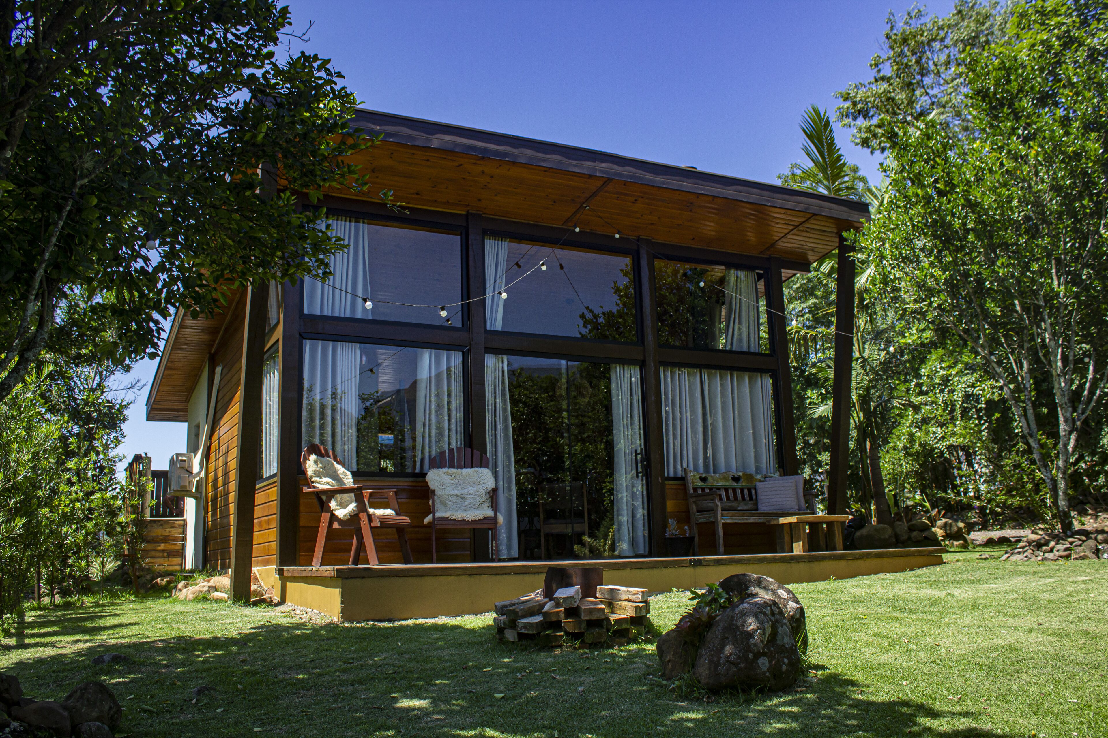Una casa moderna con ventanas amplias, una terraza de madera y un jardín cubierto de césped.