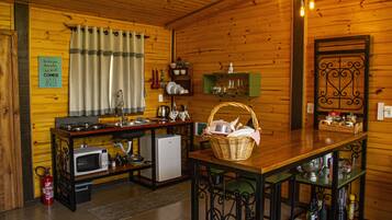 A cozy kitchen with wooden walls, a microwave, a refrigerator, and a dining table with chairs.