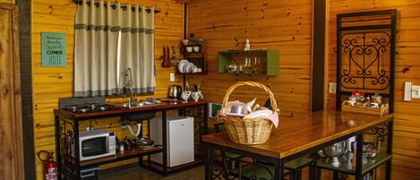 A cozy kitchen with wooden walls, a microwave, a refrigerator, and a dining table with chairs.