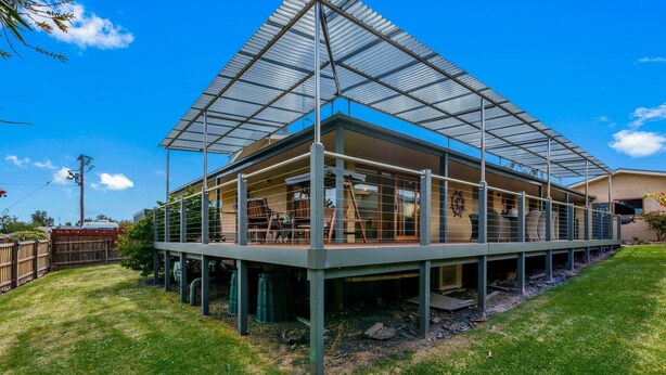 Una casa moderna con un amplio cerramiento de vidrio y una terraza de madera.