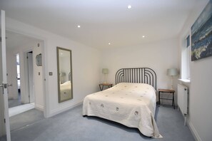 A bedroom with a bed, a large mirror, two bedside tables with lamps, and a painting on the wall. - Southbank family-friendly holiday cottage in Rye, close to the centre (Rye)