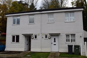 A two-story white building with a front door, two small windows, and a garage door. - Southbank family-friendly holiday cottage in Rye, close to the centre (Rye)