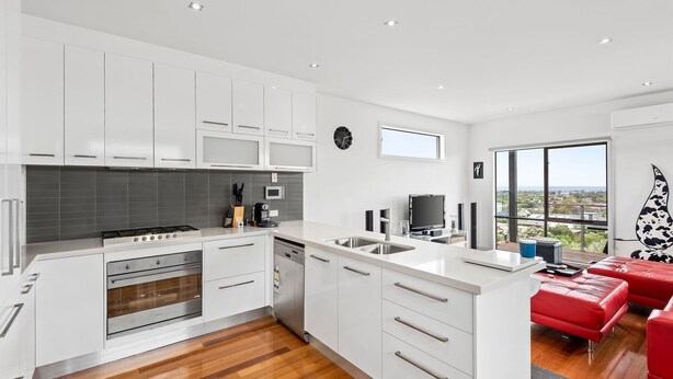 A modern kitchen with white cabinets, a stove, and a dishwasher. There's a large window offering a view of the city. - Eastern Views - Modern living with pool and table tennis. (Portarlington)