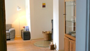 Un salon comprenant un canapé, une lampe, un meuble contenant de la verrerie et une petite table sur laquelle est posée une bougie.