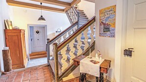 Un escalier avec une rampe en bois et des balustrades blanches, menant à une pièce dotée d’une porte blanche et d’une décoration en forme de cœur.