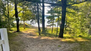 Un sendero arenoso que lleva a un banco y una vista de un lago.