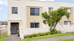 Un immeuble résidentiel moderne à plusieurs étages, doté d’une façade sobre, de grandes fenêtres et d’une pelouse bien entretenue.