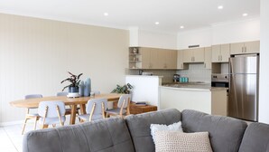 Une cuisine moderne dotée d’un îlot central, d’appareils électroménagers en acier inoxydable et de meubles de couleur claire.