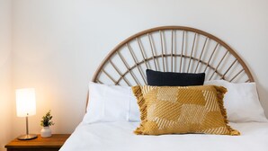 Un lit avec une tête de lit en bois, une literie blanche et des coussins décoratifs.