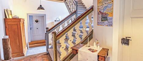 A staircase with a wooden handrail and white balusters, leading to a room with a white door and a heart-shaped decoration.