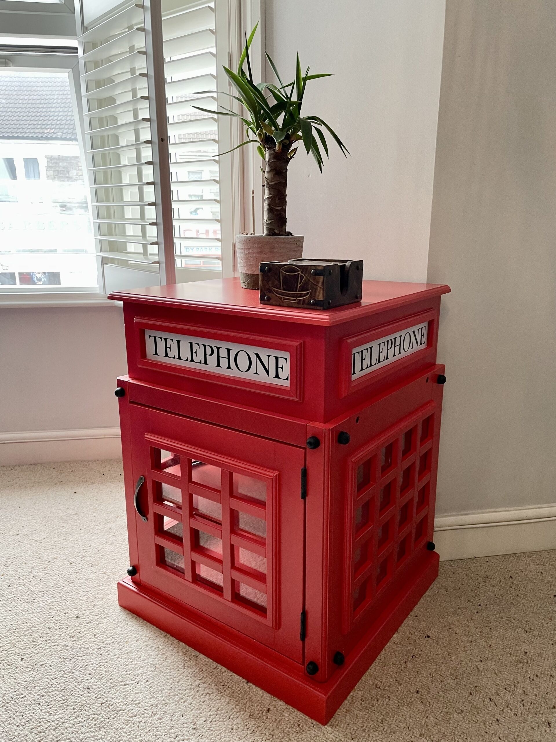 Una cabina telefónica roja con una planta en la parte superior.