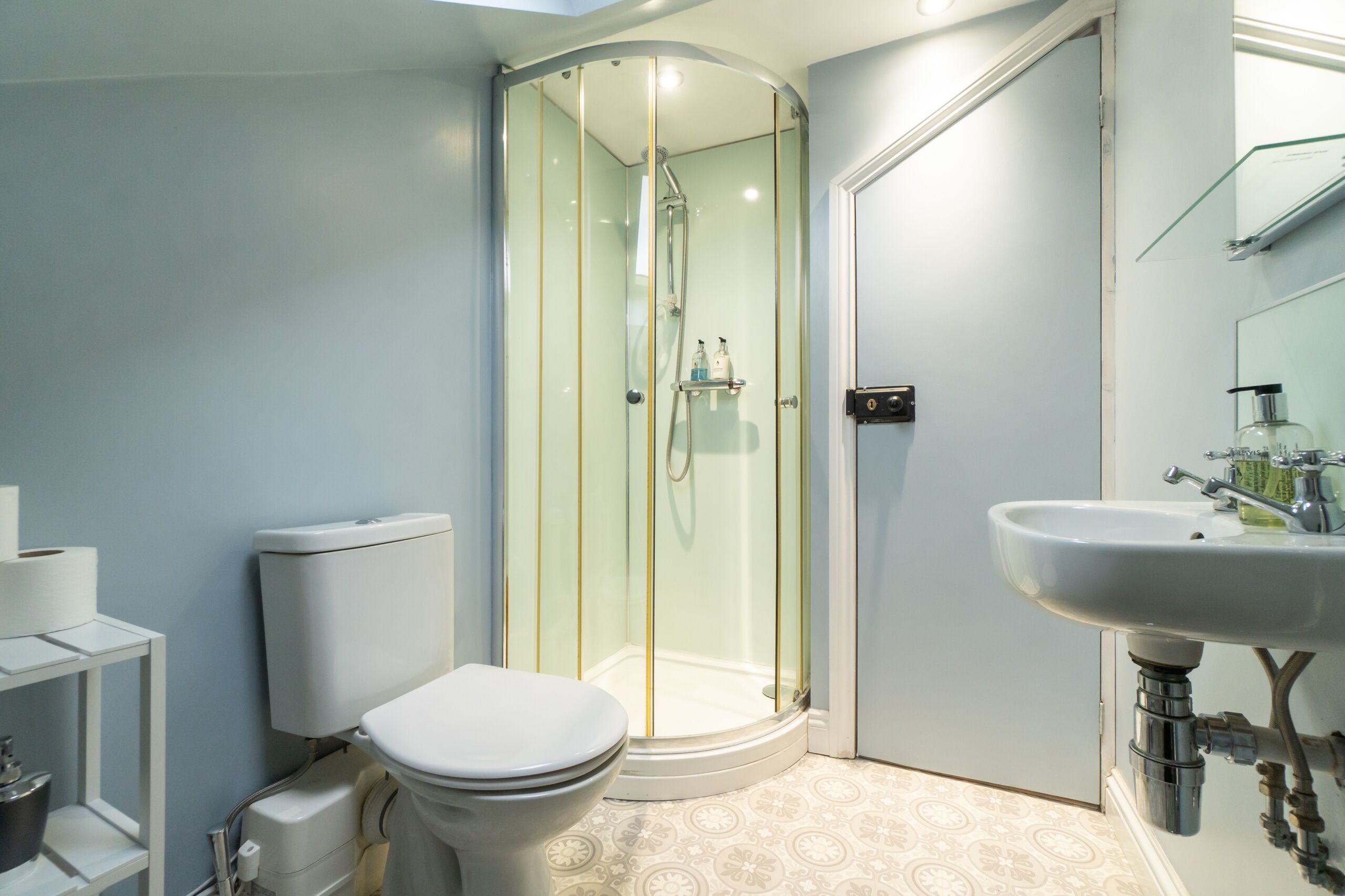 A modern bathroom with a glass-enclosed shower, a white toilet, and a sink with a mirror.