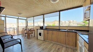 Una cocina moderna con un amplio ventanal, suelo de madera y una zona de comedor con lavadora.