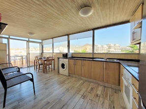 Eine moderne Küche mit großem Fenster, Holzboden und Essbereich inklusive Waschmaschine.