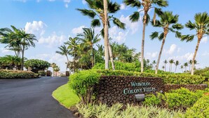 Señal de Waikoloa Colony Villas con una calle pavimentada y palmeras.