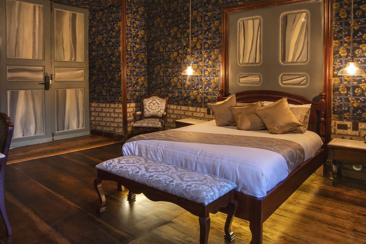 A bedroom with a large bed, a chair, and a wooden floor.
