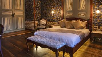 Un dormitorio con una cama grande, una silla y piso de madera.