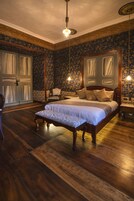 Un dormitorio con una cama grande, una silla y piso de madera.