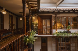 Un interior tradicional con vigas de madera, un balcón con plantas y una puerta de madera.