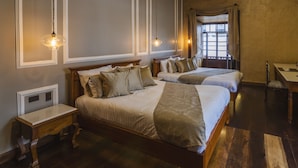 A hotel room with two beds, a wooden nightstand, a desk, and a window with curtains.