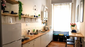 A kitchen with white cabinets, a wooden countertop, a refrigerator, a sink, and a window with curtains. - El Dorado Prati (Rome)