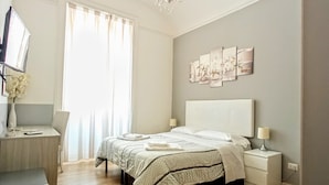 A bedroom with a bed, bedside tables, a desk, a chair, a TV, and artwork on the wall. - El Dorado Prati (Rome)