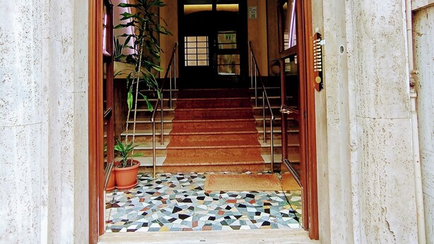 A building entrance with a tiled floor, a staircase, and a door with a number '90' on the wall. - El Dorado Prati (Rome)