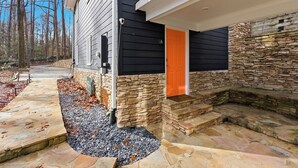 Ein Haus mit einer Steinfassade, einer leuchtend orangefarbenen Tür und einem steinernen Weg, der zum Eingang führt.