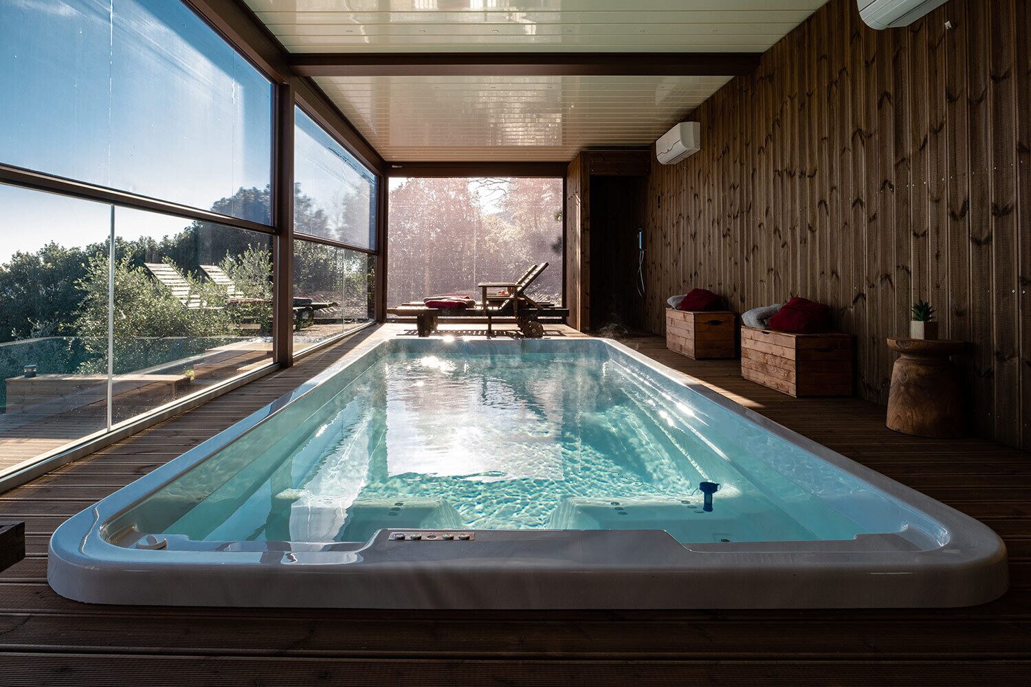Un jacuzzi en una habitación con paredes de madera y ventanas amplias.