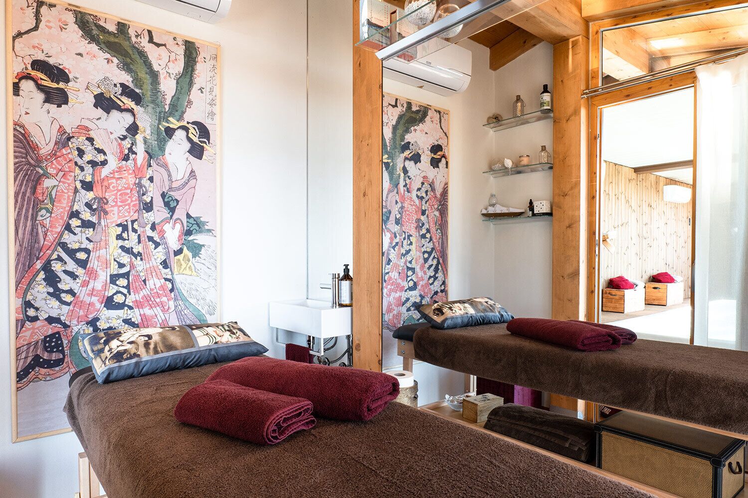 Ein Zimmer mit einem Bett, einem Spiegel, einem Waschbecken und einem großen Gemälde an der Wand.