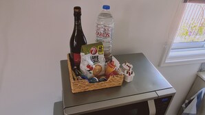 A kitchen counter with a bottle of wine, a water bottle, a bag of snacks, and a small figurine.