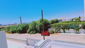 A residential area with a red car parked on the street, surrounded by greenery and houses. - STAY Nissi Heaven (Ayia Napa)