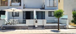 Ein modernes Gebäude mit Balkon, Sitzgelegenheit im Freien und einem kleinen Baum.