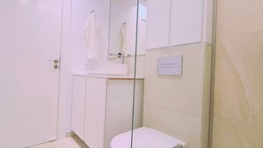 A bathroom with a toilet, a sink, and a shower area.