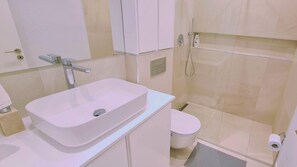 A bathroom with a white sink, toilet, and shower.