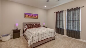 A bedroom with a bed, nightstands, a ceiling fan, a wall-mounted picture, and a window with curtains. - Cozy Houston Getaway in Gated Community (Houston)