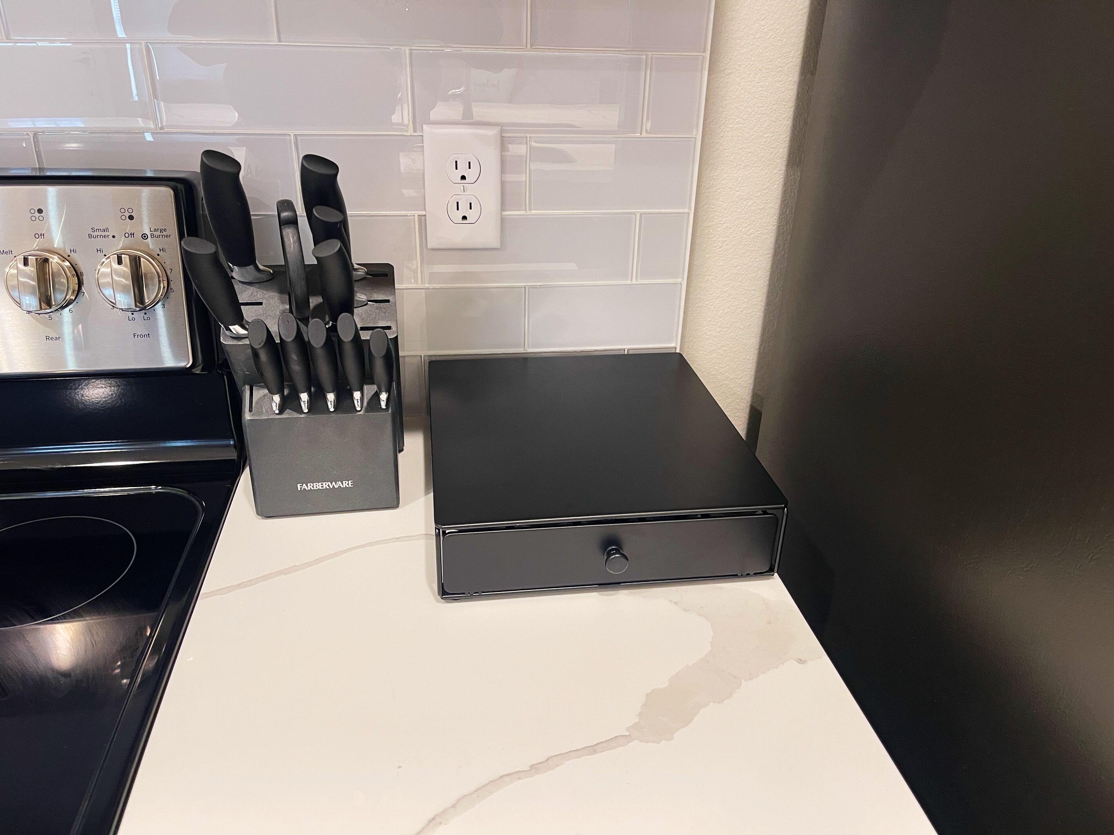 A kitchen with a stove, a knife block, and a black appliance on a countertop.