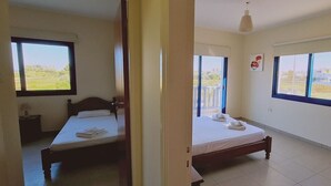 Une chambre avec deux lits, de grandes fenêtres et une vue sur l’extérieur.