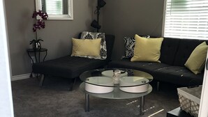 A living room with a sectional sofa, a round coffee table, a potted plant, and framed artwork on the wall. - Comfy and Cozy Centrally located in Houston!! (Houston)