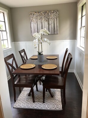 Enjoy meals in this stylish dining area with a table for four, surrounded by a beautiful abstract art piece and a vase of fresh orchids.