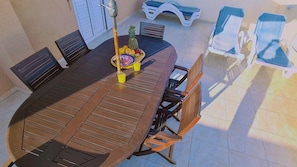 Una mesa redonda de madera con una bandeja de frutas y jugos, rodeada de sillas de madera.