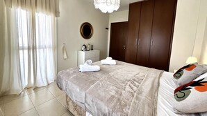 Une chambre à coucher comprenant un lit, une armoire, une table de chevet et un luminaire suspendu.