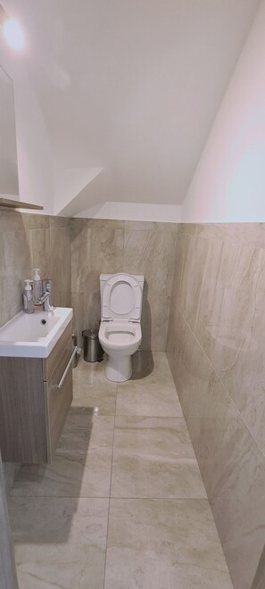 A bathroom with a toilet, sink, and storage cabinet.