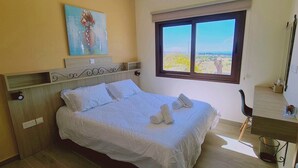 Ein Schlafzimmer mit Bett, Schreibtisch, Fenster mit Aussicht und einem Bild an der Wand.