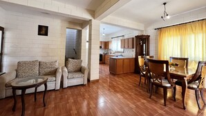 Un salón espacioso con un conjunto de sofás, una mesa de comedor con sillas y una cocina al fondo.