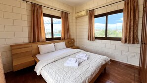 Un dormitorio con cama de madera, ropa de cama blanca y cortinas marrones.