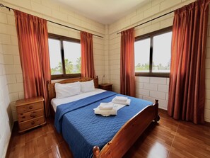 A bedroom with a wooden bed, a blue quilted bedspread, and a wooden nightstand.