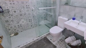 Kylpyhuone, jossa on suihku, wc, pesuallas ja lasiseinällä erotettu suihkutila.