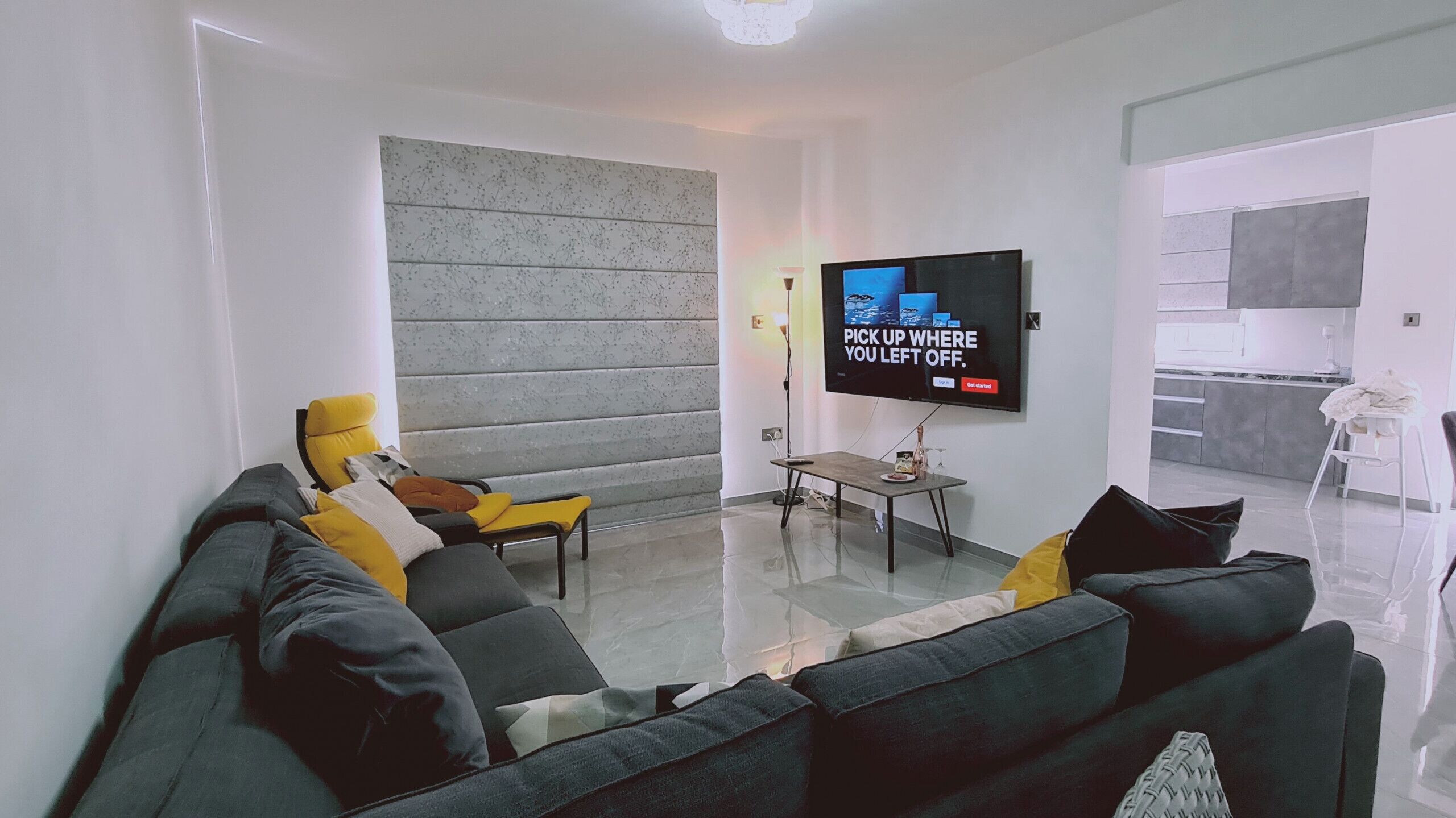 Un saló modern amb un sofà, una taula de centre i una televisió plana penjada a la paret.