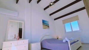 Un dormitori amb un llit, una taula de nit, una petxera i un quadre a la paret.